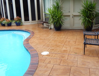 Backyard pool deck that is stamped in a ceramic tile style.